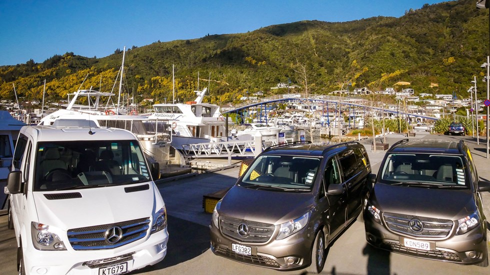 Marlborough Tour Company vehicles parked beside seafood cruise vessels in Picton, New Zealand.