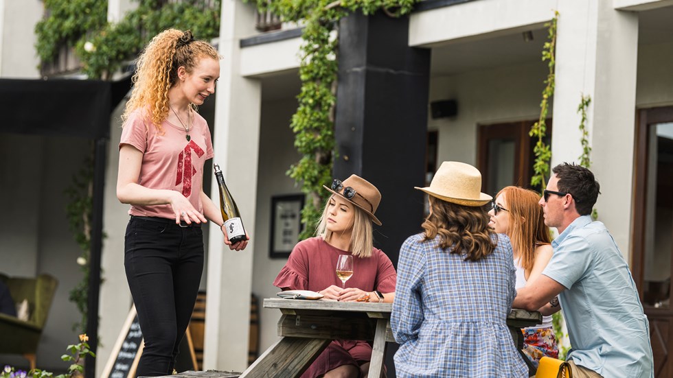 Four people sit outside during a guided wine tasting at a cellar door as part of a wine tour in Marlborough near Blenheim, at the top of New Zealand's South Island