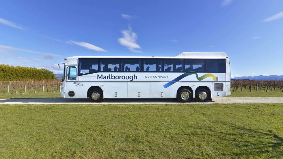 Large Marlborough Tour Co coach near Blenheim in Marlborough at the top of New Zealand's South Island parked next to Marlborough vineyards on a group wine tour.