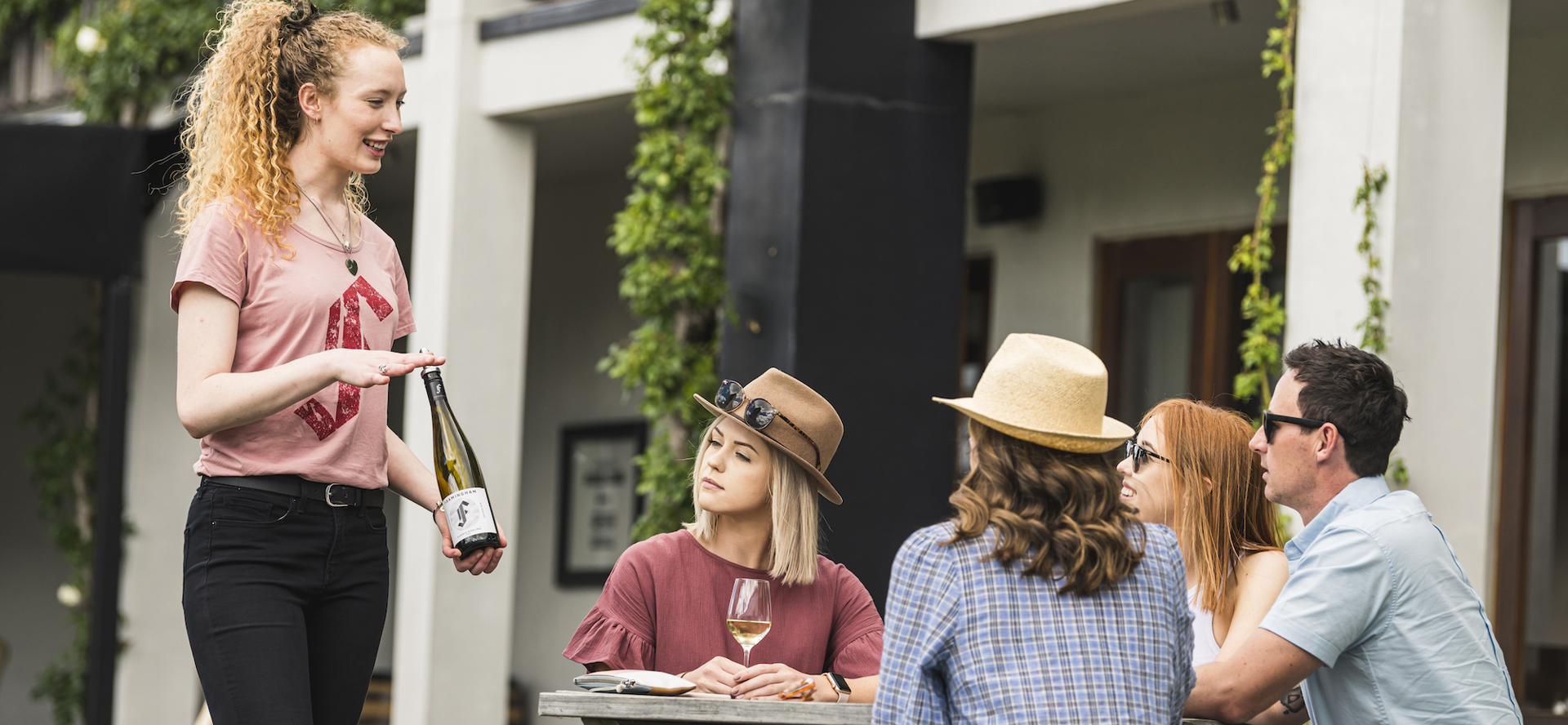 Four people on a wine tour enjoy being taken through a guided wine tasting at a winery cellar door in Marlborough, at the top of New Zealand's South Island