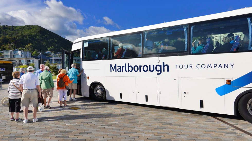 Coach with line of passenger boarding for a group tour, at Picton Marina in Marlborough at the top of New Zealand's South Island.