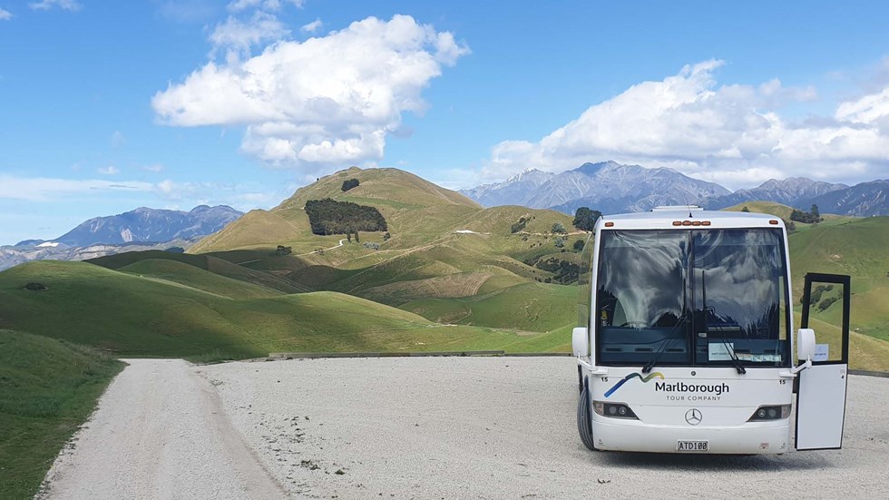 Large bus parked next to rolling hills in the country, near Blenheim in Marlborough at the top of New Zealand's South Island.