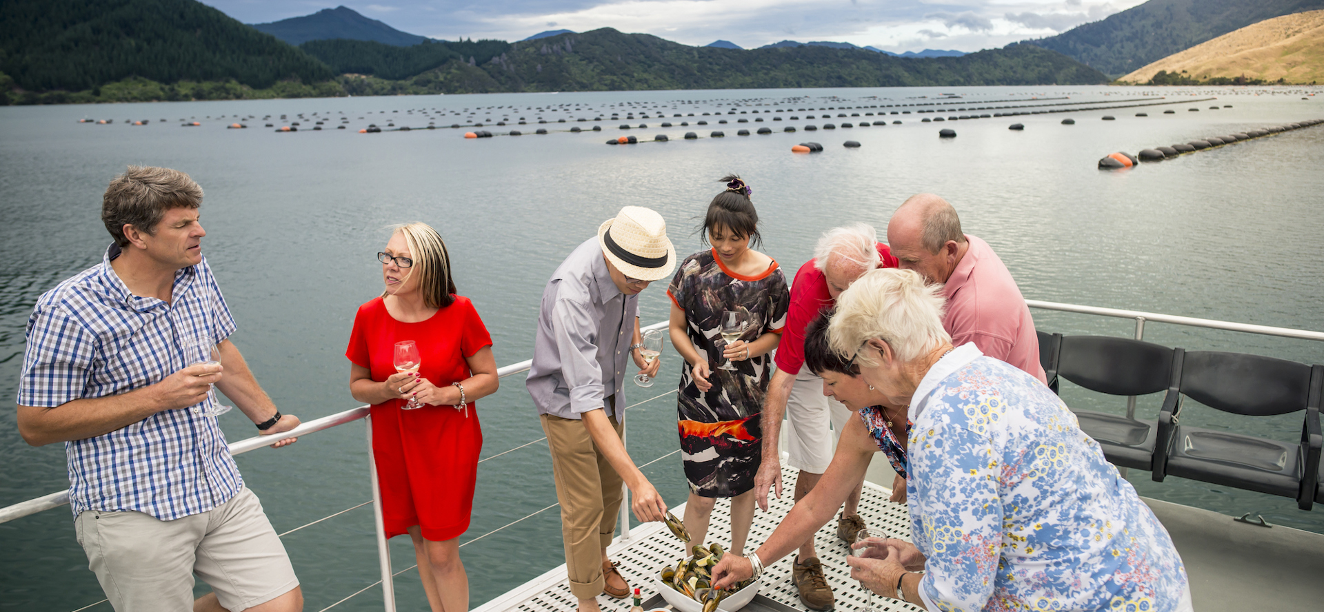 A group enjoys Greenshell mussels and wine onboard MV Spirit on a Marlborough Tour Company cruise in the Marlborough Sounds, at the top of New Zealand's South Island