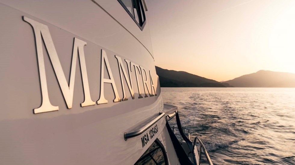 Close up of Mantra sign on the side of the boat cruising the Marlborough Sounds at sunset, at the top of New Zealand's South Island.