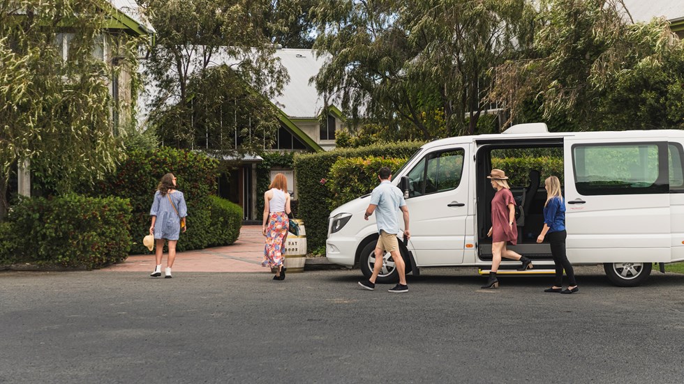 Group of four exiting a van and walking into a winery cellar door on a wine tour in Marlborough, at the top of New Zealand's South Island