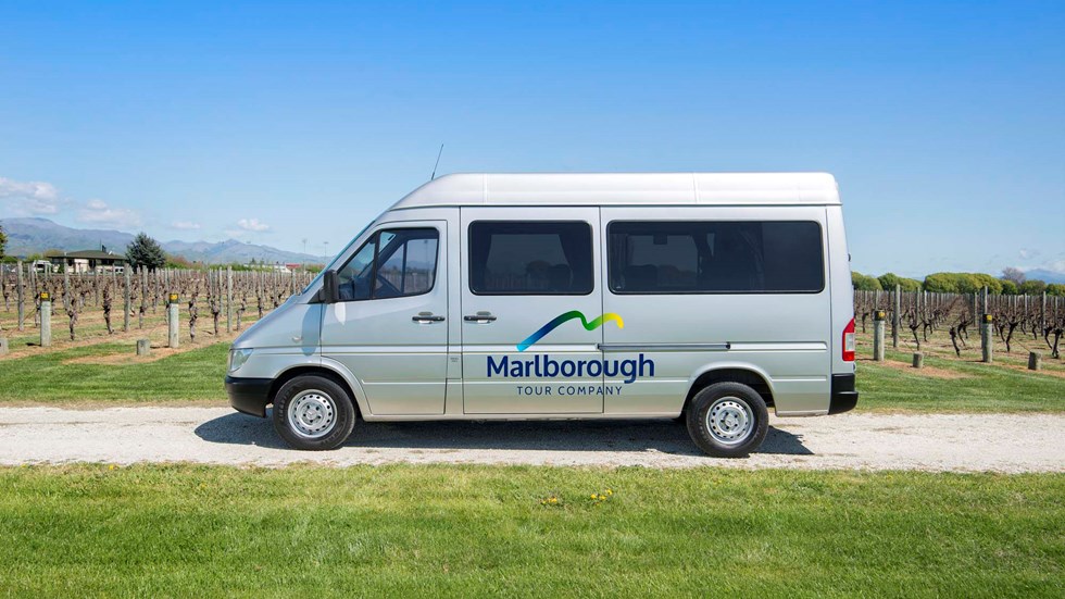Silver van with Marlborough Tour Company logo on side parked in vineyard, near Blenheim in Marlborough at the top of New Zealand's South Island.