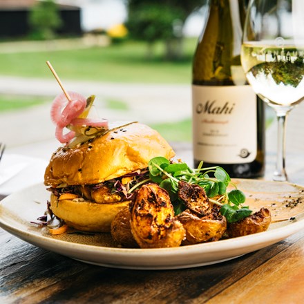 Gourmet chickpea and pumpkin burger with potatoes served with a glass of Mahi Sauvignon Blanc at the Furneaux Lodge Restaurant in the Marlborough Sounds at the top of New Zealand's South Island.