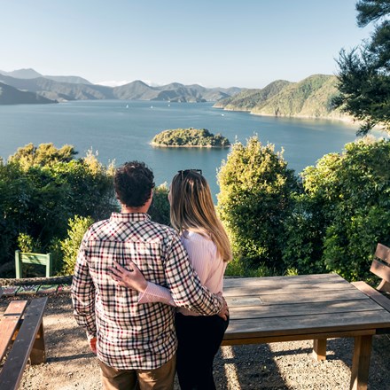 A couple look at the view over Queen Charlotte Sound/Tōtaranui from the viewpoint at Kaipupu Wildlife Sanctuary near Picton, Marlborough Sounds, New Zealand.